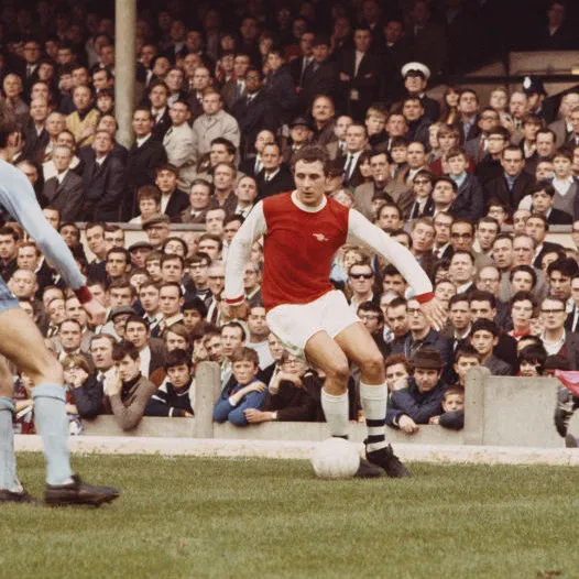 Footballer John Radford dribbling with a ball.